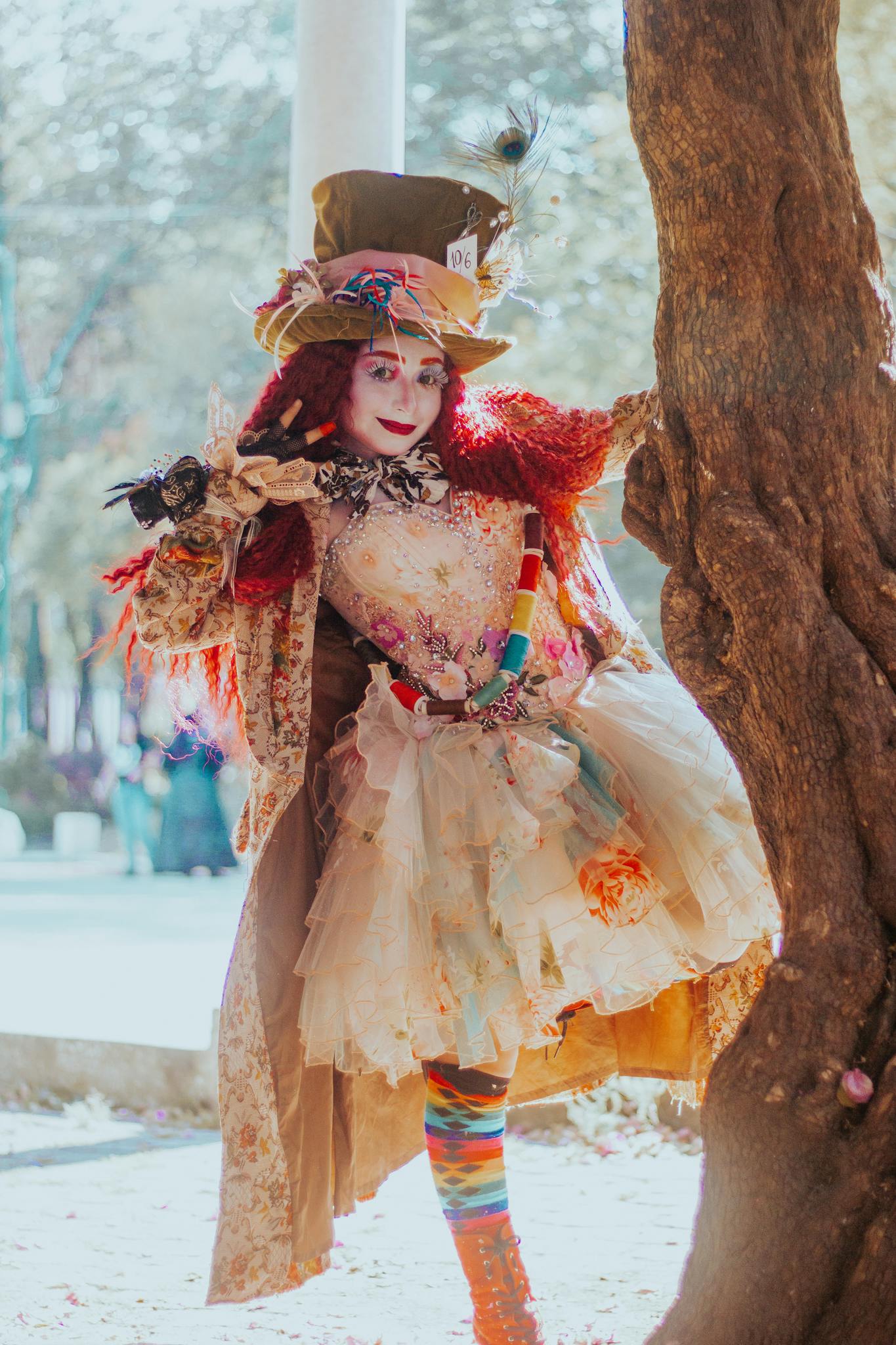 A vibrant Mad Hatter-inspired costume character poses playfully in a sunny park.