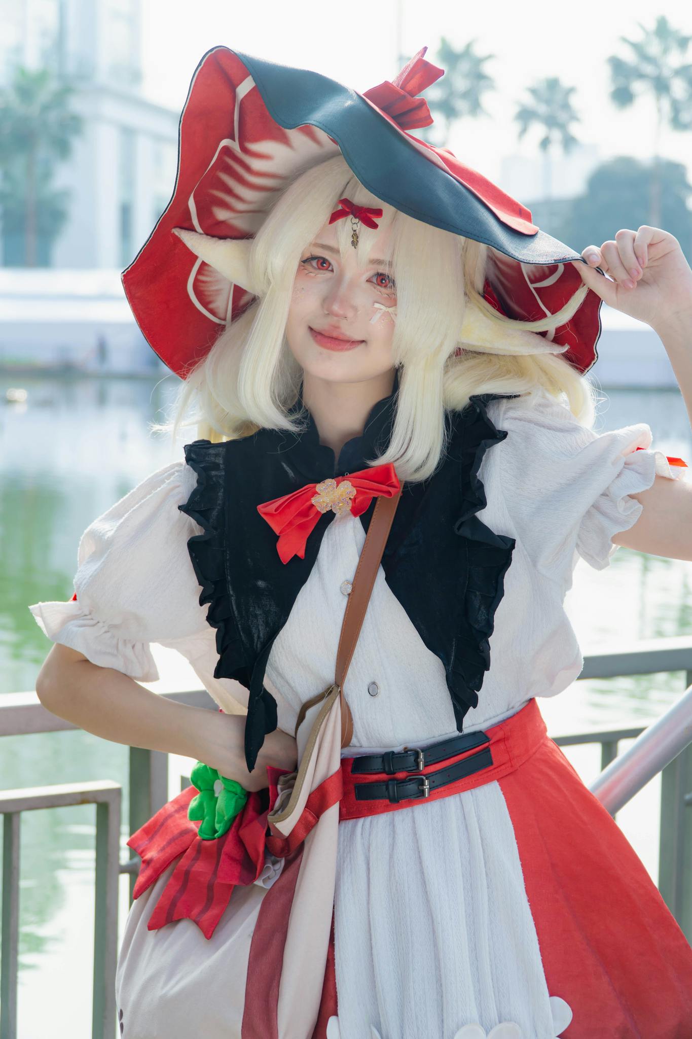Colorful cosplayer in detailed costume by a serene waterfront.