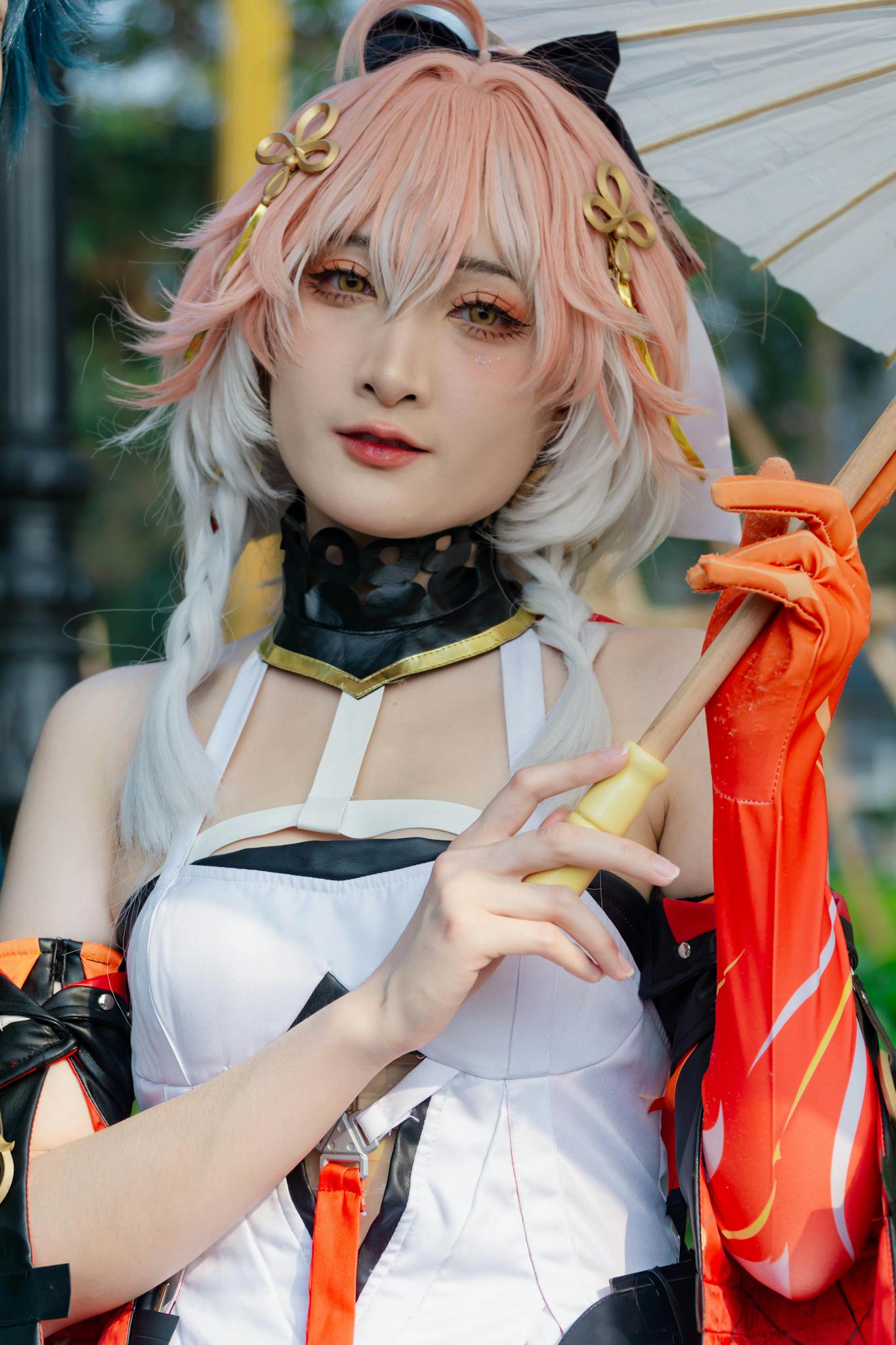 Detailed portrait of a cosplayer in vibrant costume holding a parasol outdoors.