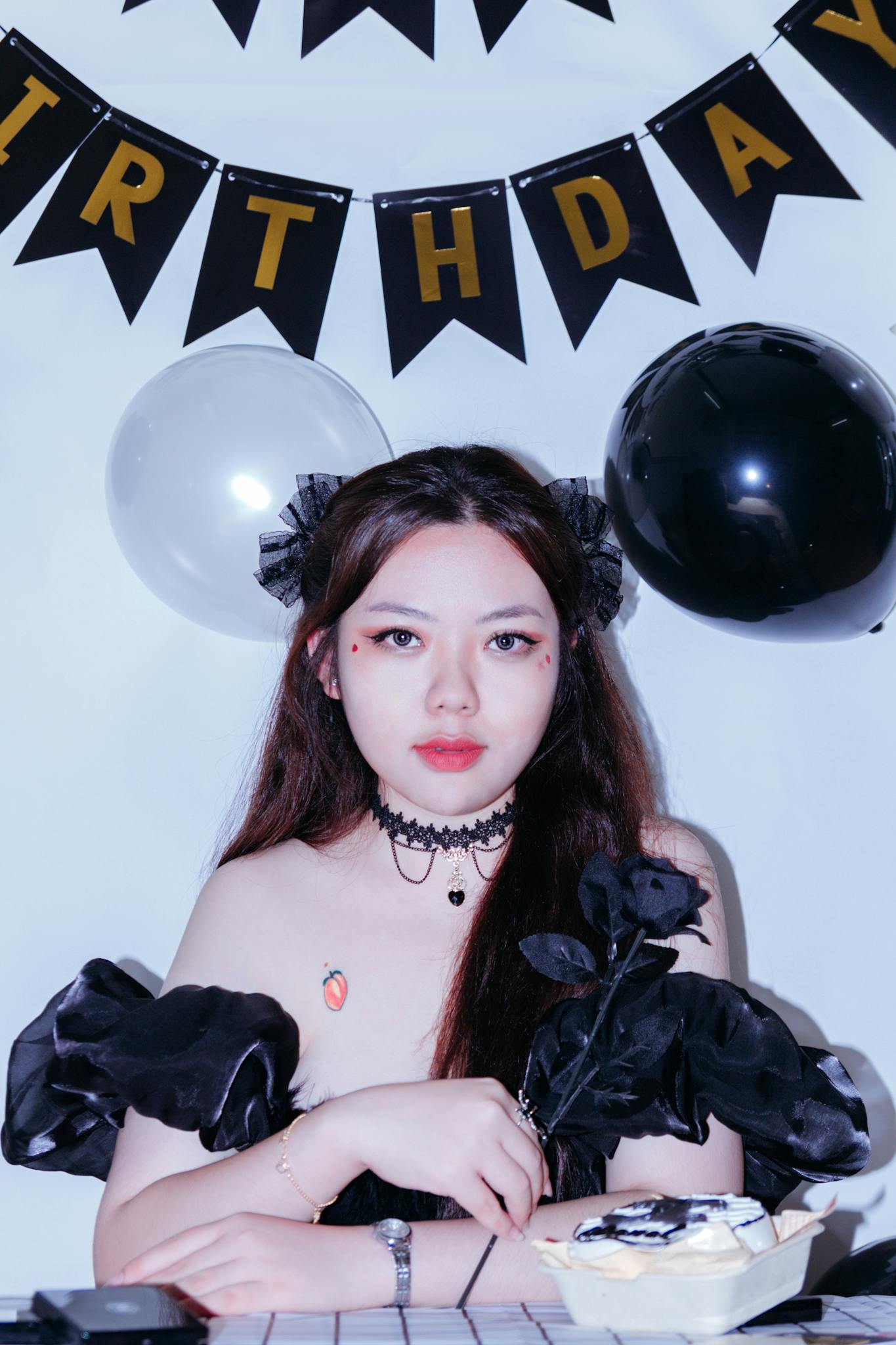 Elegant woman in black outfit at a birthday party with festive decorations.