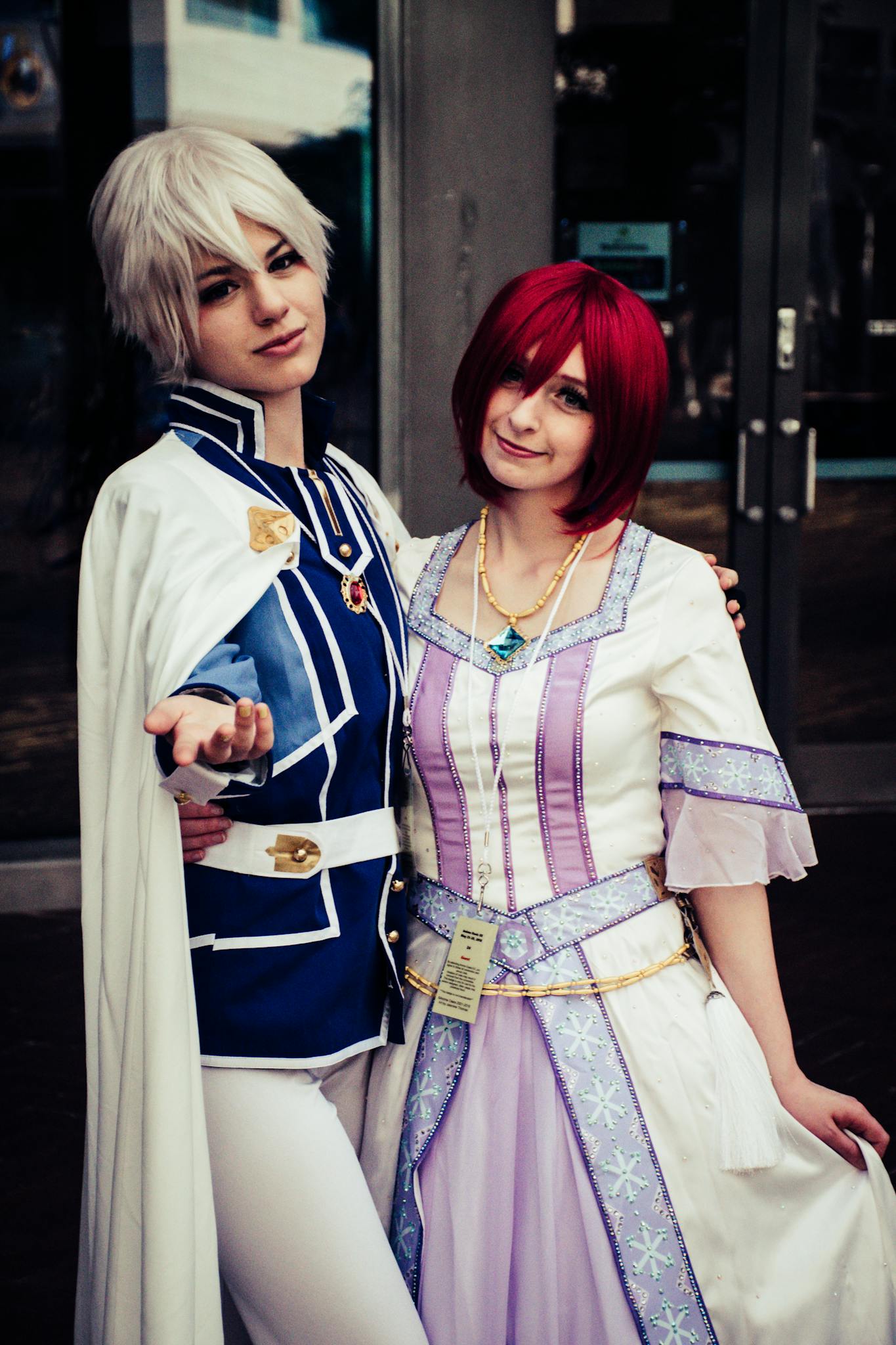 Two cosplayers in detailed costumes pose confidently at a photoshoot.